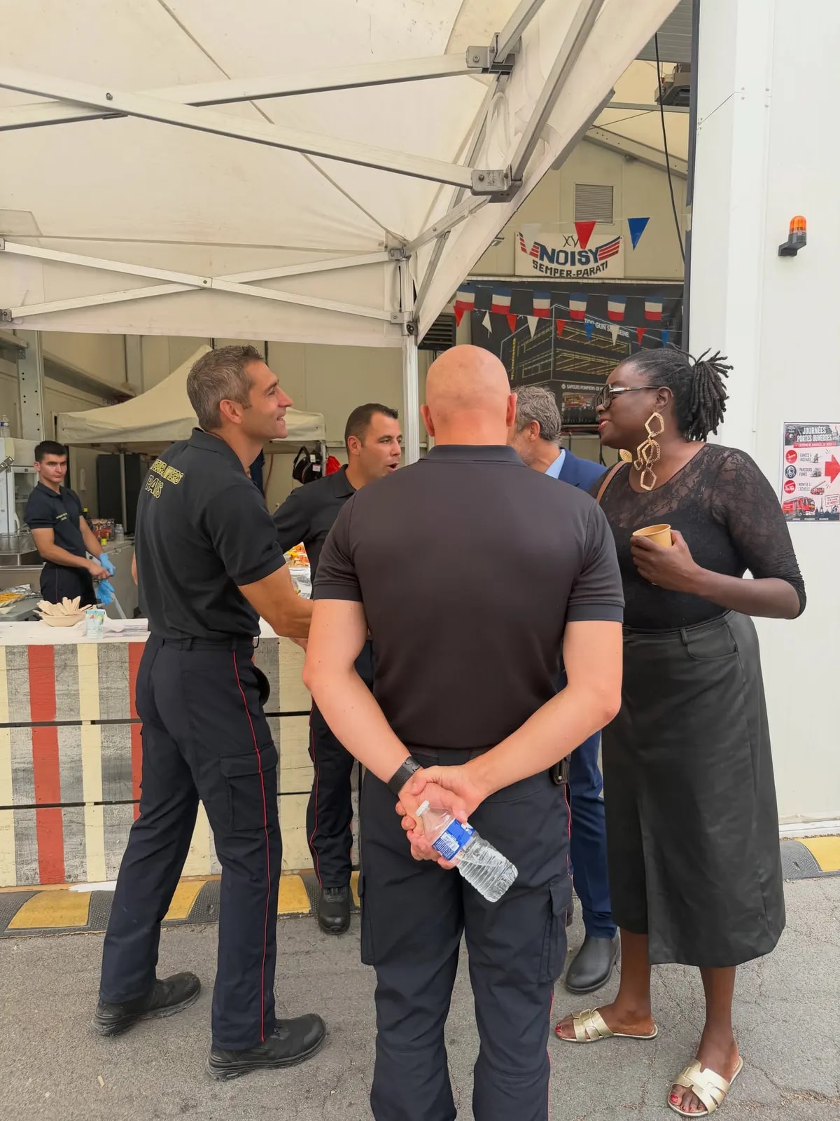 Sous un barnum, un pompier en tenue s’entretient avec trois personnes venues au stand.
