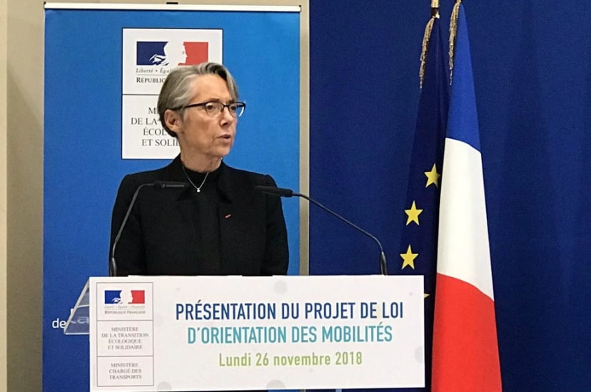 Femme au pupitre devant les drapeaux français et européen : « Présentation du projet de loi d'orientation des mobilités »