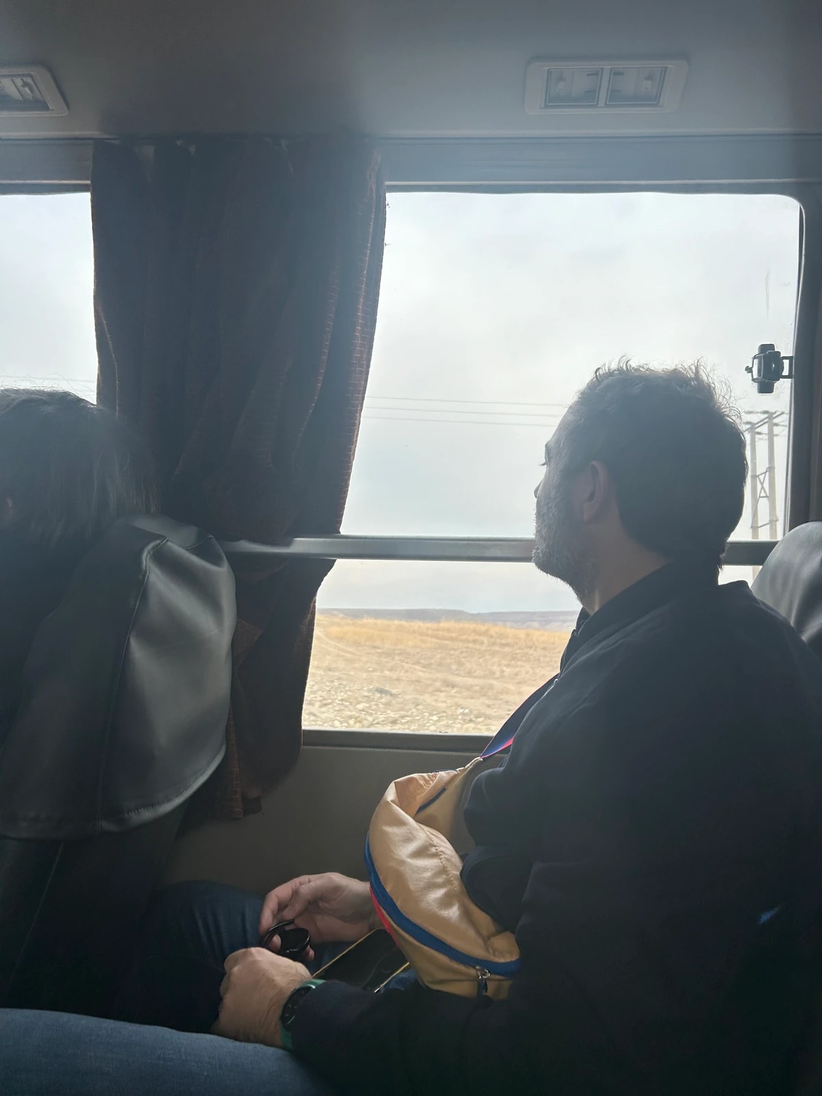 Passagers assis dans un autocar, regardant par la fenêtre un paysage de plaine.