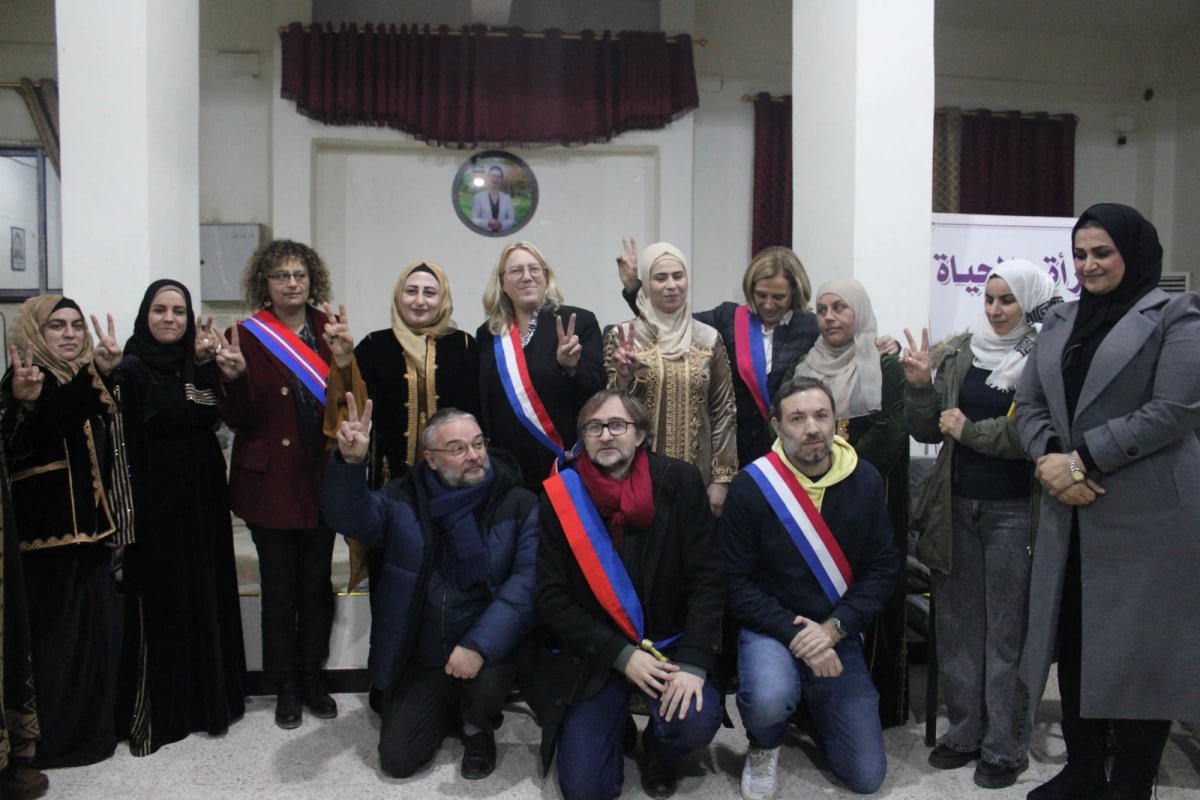 Une quinzaine de personnes en salle de réunion, dont des élus en écharpe tricolore ; plusieurs font le signe de la victoire.
